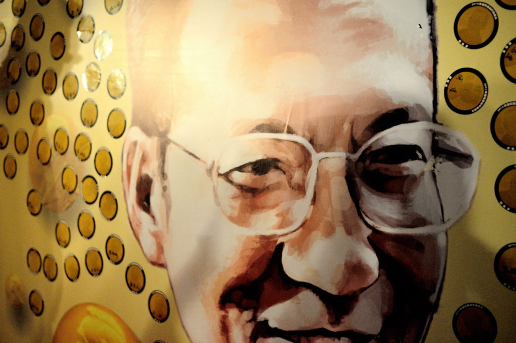Liu Xiaobo ler ett snett leende och hans glasögon utan bågar lyser i det starka ljuset från sidan.