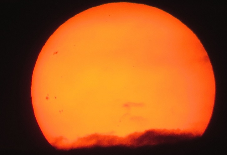 Solen. Den är orange med lite mörka moln framför i nederkant.