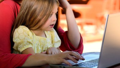 En flicka som tittar på en laptop.