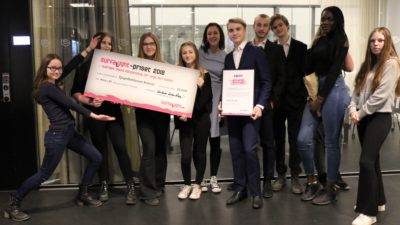 Delar av klass 8F står uppradade framför kameran. Några av eleverna håller i en stor check på 25000 kronor. En annan elev håller i ett diplom.
